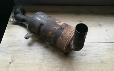 Zardzewiały, zużyty filtr DPF na drewnianym blacie.