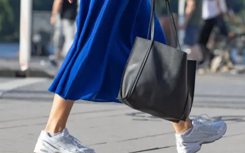 Ein blaues Kleid mit weißen Sneakern zum Kleid und einer schwarzen Tasche.