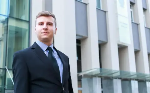 Mężczyzna w garniturze przed nowoczesnym budynkiem.