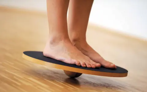Piedi su una tavola di equilibrio, utili per esercizi di riabilitazione per distorsione caviglia.