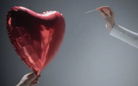 Czerwone serce-balon trzymane w dłoni, druga dłoń z igłą zbliża się do niego. Symbolizuje współżycie w trakcie rozwodu, które jest na skraju pęknięcia.