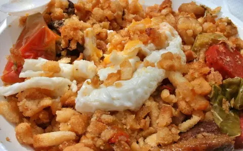 Plato de migas con huevo frito, pimientos y tomate, un delicioso ejemplo de comida típica de Jaén.