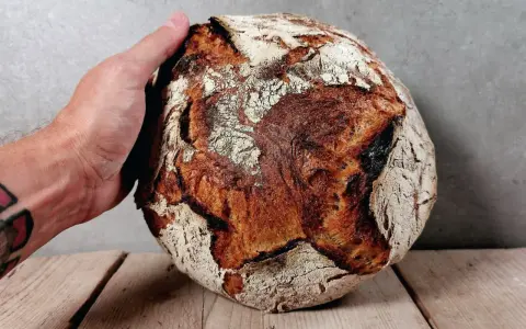 Eine Hand hält ein knuspriges Brot. Perfekt zum Bier!