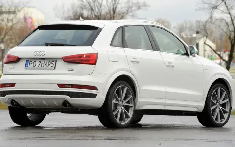 Biały SUV Audi Q3, idealny suv do 70 tys. zł, z polskimi tablicami rejestracyjnymi PO 7H495, widoczny z tyłu i z boku.