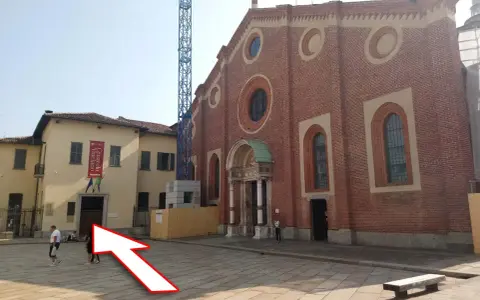 Plac przed kościołem z banerem "Cenacolo Vinciano". Bilety na Ostatnią Wieczerzę można kupić w pobliżu.