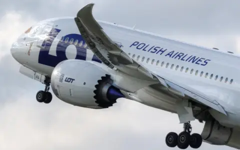 Samolot LOT Polish Airlines w locie, widok z boku na silnik i skrzydło.