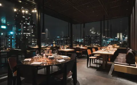 En mysig restaurang i Stockholm med vacker utsikt över stadens ljus på natten. Eleganta bord med dukning och bekväma sittplatser.