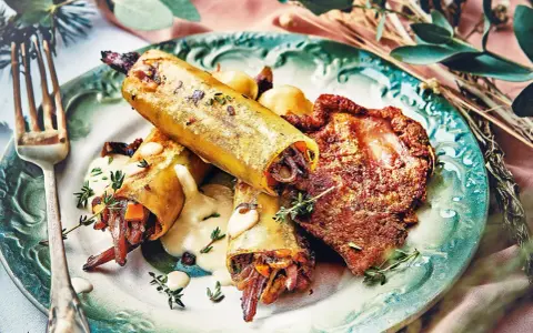 Un délicieux repas d'anniversaire léger : cannellonis farcis à la viande et légumes, accompagnés d'une sauce crémeuse et d'une tranche de viande croustillante.