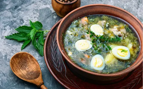 Zupa szczawiowa tradycyjna z jajkiem i ziemniakami, podana w glinianej misce, obok świeży szczaw i drewniana łyżka.