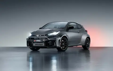 Szary Toyota GR Yaris GR-FOUR z agresywnym przednim zderzakiem i czarnymi felgami, gotowy do podboju dróg.