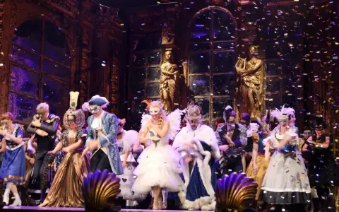 Scena z "Upiora w Operze" – barwny bal maskowy z konfetti.