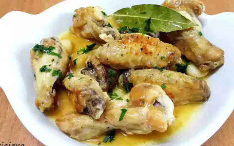 Alitas de pollo al ajillo, doradas y jugosas, servidas en una salsa con ajo y perejil fresco. ¡Un manjar irresistible!