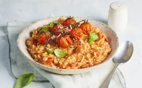 Cremiges Tomaten Risotto, garniert mit frischen Basilikumblättern und gerösteten Kirschtomaten. Ein Genuss für jeden Liebhaber italienischer Küche.