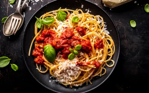 Talerz spaghetti z sosem pomidorowym, parmezanem i bazylią.