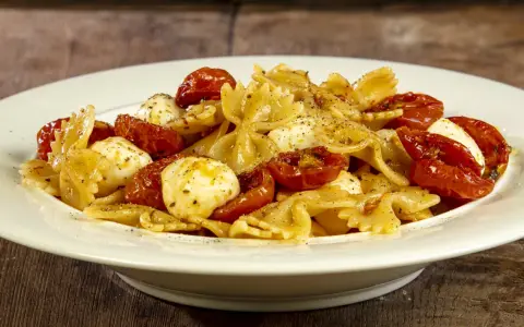 Farfalle con pomodorini confit, mozzarelline e un tocco di acciughe. Un piatto semplice e gustoso.