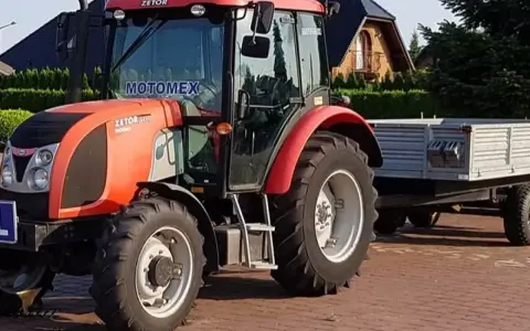 Czerwony Zetor z przyczepą, gotowy do pracy. Marzenie o własnym polu i prawo jazdy na traktor staje się rzeczywistością.