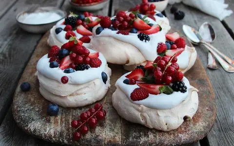 Små pavlovakakor med vispgrädde och färska bär som jordgubbar, hallon, blåbär och vinbär. En härlig sommardessert!