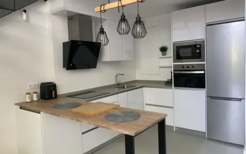 Cocina moderna con isla, electrodomésticos integrados y lámparas colgantes. Ideas para como diseñar una cocina funcional y elegante.