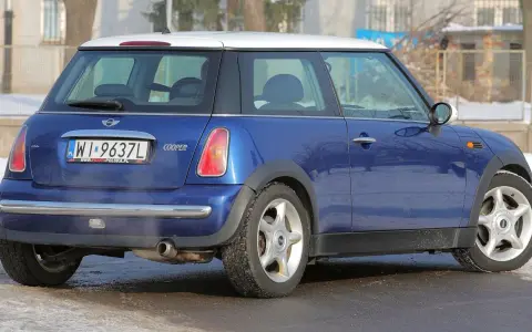 Niebieski Mini Cooper R50 z białym dachem, zaparkowany na zaśnieżonej drodze.