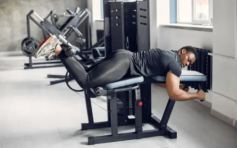 Man utför liggande lårcurl på ett gym.