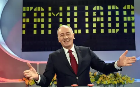 Uśmiechnięty prowadzący w garniturze na tle planszy z zielonymi polami, jak w Familiadzie. Ile lat ma ten program?