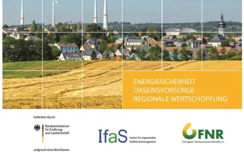 Windräder über einem Dorf und goldenen Feldern. Die Frage, welche erneuerbare Energie die beste ist, wird hier visuell angedeutet.