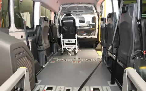 Innenraum eines Rollstuhlfahrzeugs, das als Taxi-Ersatz dient. Sitze und Rollstuhlhalterungen sind sichtbar.