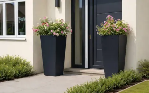 Zwei hohe, dunkle Pflanzkübel mit rosa und weißen Blüten schmücken den Eingangsbereich. Ein schöner Weg, den hauseingang zu bepflanzen.