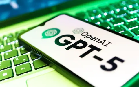 Ekran smartfona z logo OpenAI i napisem GPT-5 leży na podświetlanej zielonej klawiaturze.
