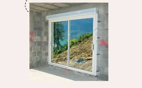 Fenêtre coulissante en PVC installée dans un mur en parpaings, offrant une vue sur un paysage montagneux. Idéal pour apprendre comment poser une fenêtre de toit.