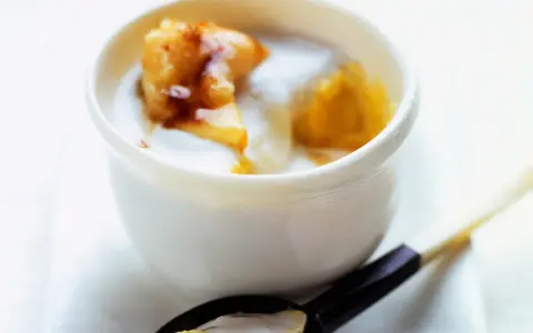 Délicieux dessert lait de coco crémeux avec des morceaux de fruits caramélisés. Une cuillère en est prête à être dégustée.