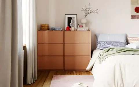 Ordnung im Schlafzimmer: Ein Nachttisch mit Schubladen, Bettwäsche und Dekoration.