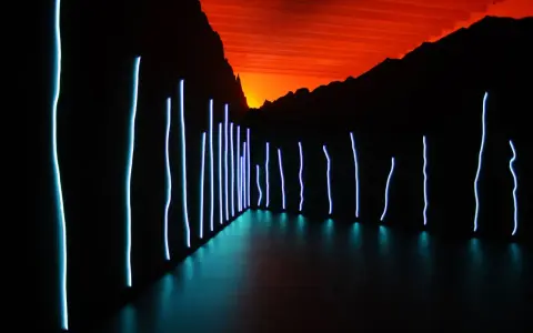 Installation lumineuse de Claude Lévêque, avec des néons bleus sur fond de ciel orangé et de montagnes sombres.