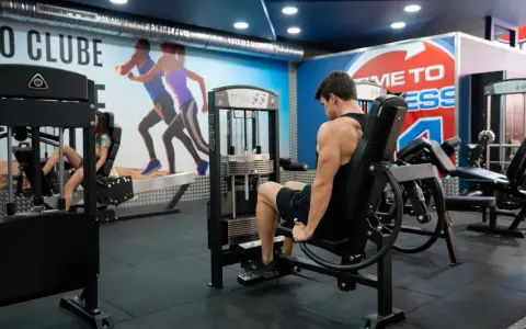 Man tränar ben på en **floor press**-maskin i ett modernt gym.