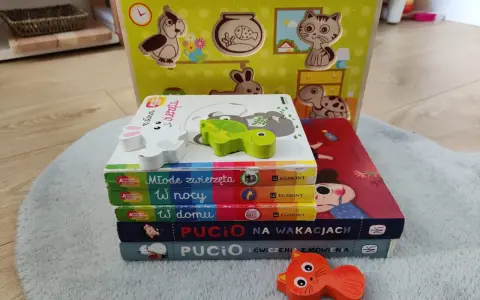 Zabawki dla 1,5 rocznego dziecka: drewniana układanka ze zwierzątkami i stos książeczek "Akademia Mądrego Dziecka" oraz "Pucio".