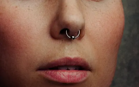 Zbliżenie na twarz z kolczykiem w nosie (septum). Czy septum boli? To pytanie zadaje sobie wiele osób przed piercingiem.