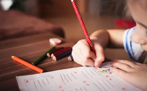 Dziecko zmagające się z dysleksją, dysgrafią, dysortografią i dyskalkulią pisze kredkami.