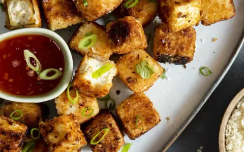 Krispiga, gyllene tofu-bitar serveras med en söt chilisås. Ett perfekt tofu recept för en snabb och god måltid.