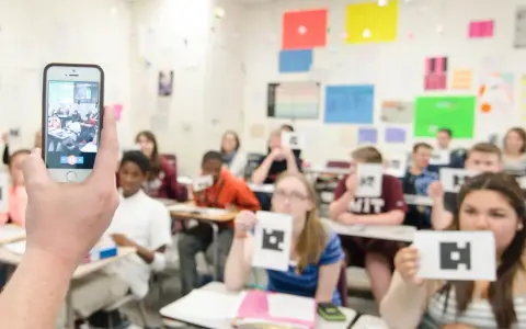 Classe che usa un'app per la scuola, con studenti che mostrano carte con simboli.