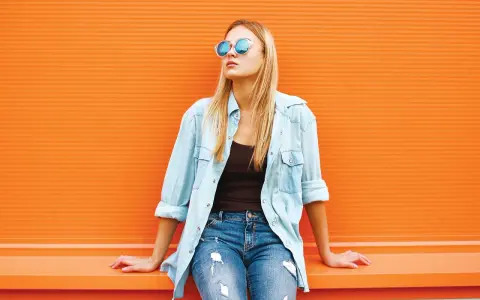 Dziewczyna w okularach i jeansach, z luźną koszulą jeansową z czym łączyć – idealny casualowy look na co dzień.