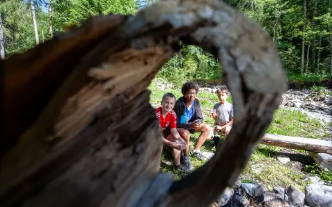 Trois enfants profitent d'une pause en forêt, rappelant l'importance du respect des locaux et de la nature.