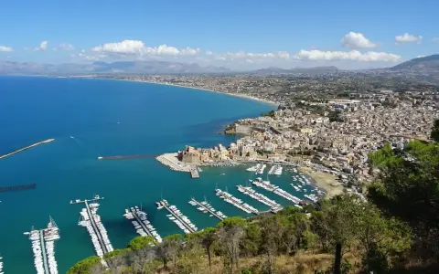 Vista panoramica di Castellammare del Golfo, con il castello, il porto turistico pieno di barche e la costa siciliana.