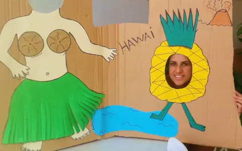 Divertido photocall hawaiano casero con una figura de bailarina y una piña con cara sonriente. ¡Perfecto para unas fotos tropicales!