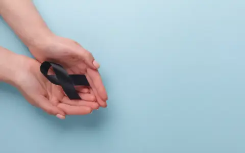 Dłonie trzymają czarną wstążkę, symbol żałoby. To znak, co się mówi, jak ktoś umrze.