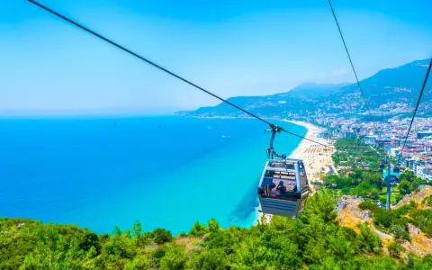 Kolejka linowa nad turkusowym morzem i plażą w Alanyi. Widok z góry na miasto i wybrzeże. Czy Alanya jest bezpieczna? Tak, wygląda na spokojną i piękną.