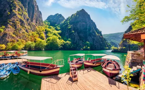 Malownicze macedonia atrakcje: łodzie i kajaki czekają na wodach kanionu Matka, otoczonego stromymi, zielonymi górami.