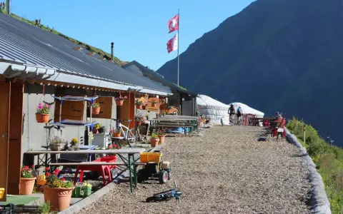 Górskie schronisko, idealne na przerwę podczas tour de Mont Blanc. Dwa rowery, szwajcarskie flagi i piękne widoki.