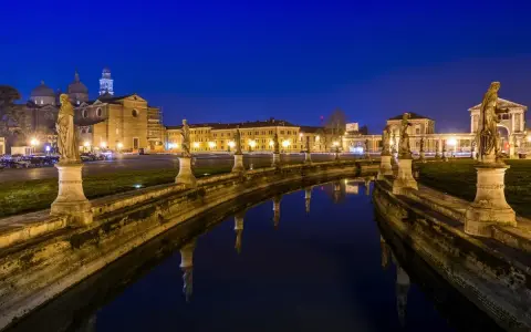Prato della Valle di notte, un'idea di cosa vedere a Padova in un giorno. Statue e riflessi sull'acqua creano un'atmosfera magica.