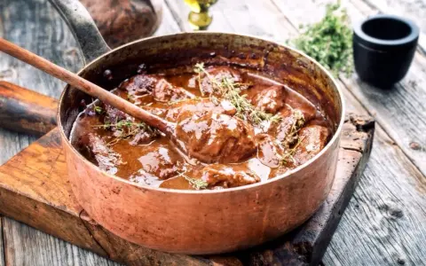 Un saporito brasato di manzo, cotto lentamente in una pentola di rame, guarnito con timo fresco.