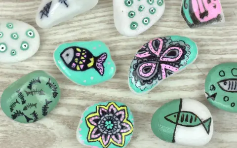 Ideas para pintar piedras de playa: peces, flores y diseños abstractos en tonos turquesa, blanco y rosa.